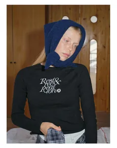 Detail of embroidered 'Rest & Recreation' lettering on black knit wool scarf and top