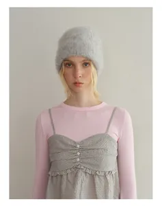 Detail view of fuzzy alpaca wool knit beanie in light grey worn by a female model