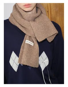Detailaufnahme des kamelfarbenen Strickschals aus Wollmischung mit Markenetikett
