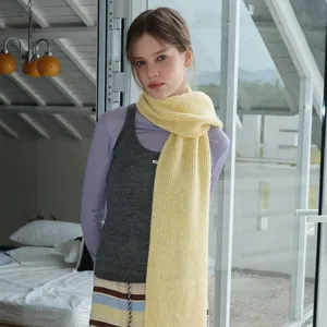 Light yellow long knitted wool scarf with chunky ribbed texture on female model