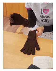 Detailed close-up of dark brown knit wool gloves with warm ribbed cuffs on a wooden desk