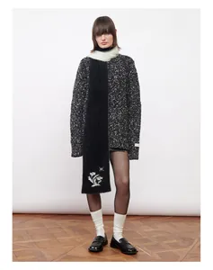 Détail d'une écharpe noire en faux vison avec broderie florale et texture de pull en maille