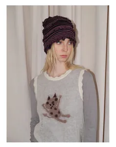 Détail d'un bonnet en tricot rayé violet et noir avec bords ondulés de style Y2K