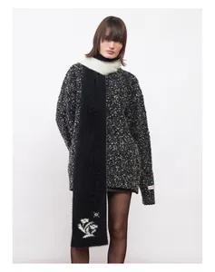 Gros plan d'une écharpe en mohair noir avec motif floral blanc et texture en maille douce