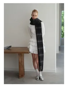 Close-up of thick grey and black plaid wool scarf featuring classic decorative fringes