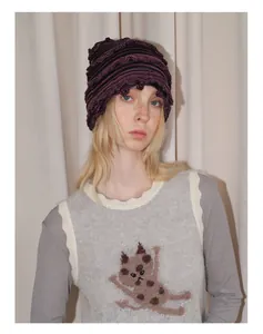 Détail de la texture d'un bonnet y2k en laine tricotée à rayures violettes et noires