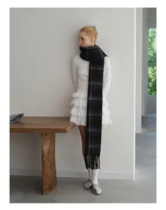 Close-up of extra long black and grey checkered wool blend scarf with tassel details