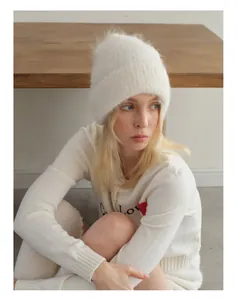 Detail of soft white alpaca knit beanie paired with a minimalist cream cardigan