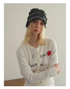 Détail du cardigan en maille blanc avec broderie coeur rouge et motif de lettres