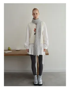 Volledig beeld van alpaca sjaal gecombineerd met gebreid vest en wit overhemd outfit