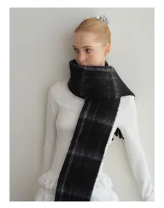 Close-up of black and grey plaid wool blend scarf with fringe and soft brushed texture