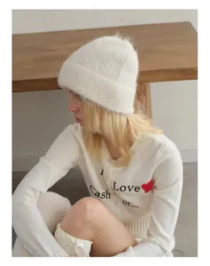 Detail of white alpaca wool knit beanie paired with a minimalist white heart cardigan
