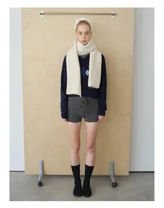 Detailed knit texture of a cream wool blend cable scarf with blue diamond vest