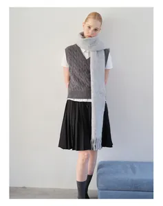 Detail eines hellgrauen Alpaka-Wollschals mit Fransen und einer grauen Strickweste