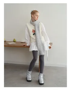 Detail van pluizige grijze alpaca wollen sjaal gecombineerd met geborduurd vestje