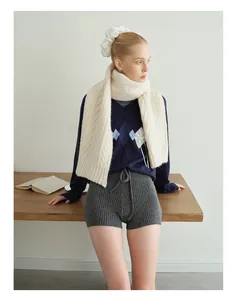 Detail of white chunky knit cable scarf paired with dark blue v-neck diamond vest