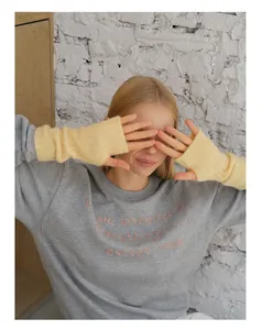 Detail of light yellow ribbed knit fingerless gloves paired with an embroidered sweatshirt