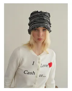 Détail du bonnet en laine rayé et du cardigan avec décoration de cœur rouge floqué