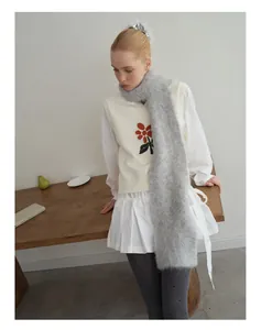 Detail van grijze alpaca wollen sjaal met een gebreid vest en witte plissé rok