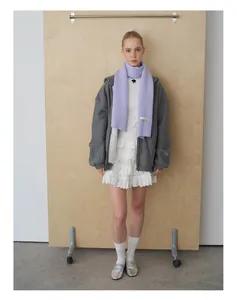 Detailansicht von lila Strickschal mit Rippenmuster und einem weißen Spitzenrock