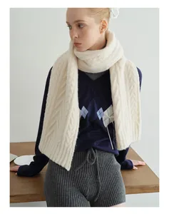 Detail of off-white chunky cable knit wool scarf paired with a navy argyle sweater