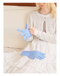 Close-up of sky blue thick-knit wool gloves on model in cozy indoor setting