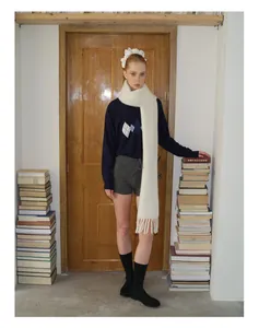 Modell trägt weichen weißen Alpaka-Wollschal mit marineblauem Stepp-Sweatshirt und Shorts