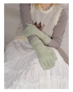 Close-up of light green knit wool gloves featuring ribbed cuffs on a model arm