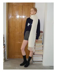 Künstlerische Aufnahme eines weißen Alpaka-Wollschals mit Fransen und marineblauem Pullover