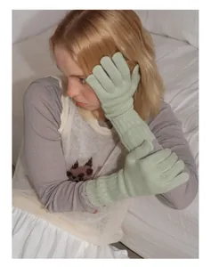 Close-up of mint green wool knit gloves showing soft texture and long sleeve design