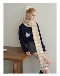 Close-up detail of soft wool blend scarf with textured knit stripes and long fringe tassels