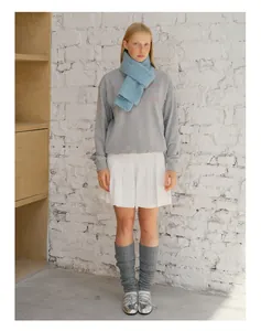 Detail showing soft sky blue wool knit scarf styled with grey sweatshirt and white pleated skirt