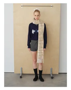 Detailed view of long striped fringe scarf paired with a V-neck argyle knitted sweater