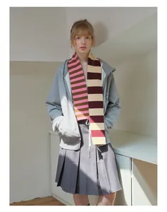 Detailed styling of a long striped merino wool scarf paired with a grey zip-up hoodie