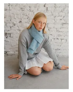 Close-up of a soft sky blue knitted scarf paired with a grey sweatshirt and white skirt