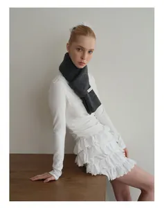 Detail eines weichen dunkelgrauen Wollstrickschals kombiniert mit einem weißen Spitzenrock