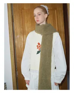 Detail eines weichen olivgrünen Alpaka-Wollschals kombiniert mit einer floralen Strickweste