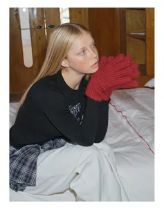 Detailaufnahme roter grob gestrickter Wollmischhandschuhe an einem Modell in Innenraum