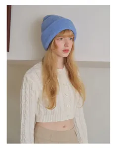 Detailed cable knit pattern on off-white cardigan paired with sky blue beanie hat