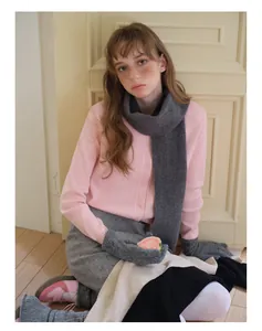 Détail d'une écharpe en pure laine avec un cardigan en maille rose et des gants gris
