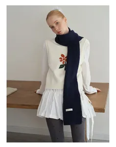 Details des dunkelblauen Wollschals mit Etikett und Strickweste mit Blumenstickerei