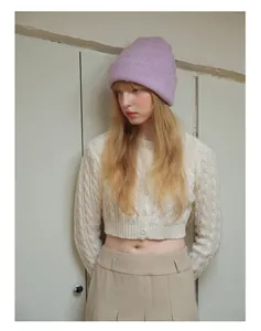 Close-up of a lilac knit beanie paired with a cream-colored cable knit cardigan outfit