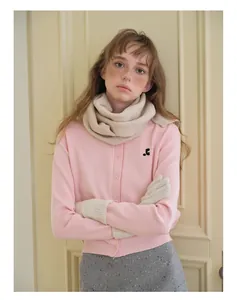 Détail d'un cardigan en tricot rose avec écharpe en laine et gants pour un look d'hiver