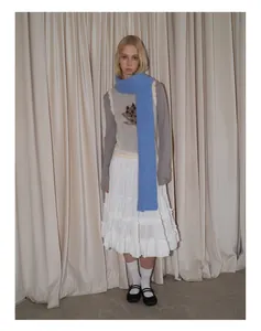 Detailed layered outfit featuring a light blue knitted scarf and white tiered skirt