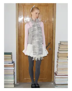 Detail shot of a black and white gradient knit wool scarf with soft fringe tassels on a model