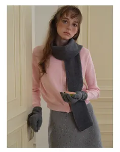 Détail d'une écharpe en laine grise et gants assortis avec un cardigan rose
