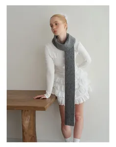 Detail of dark gray wool knit scarf styled with white lace top and pleated skirt