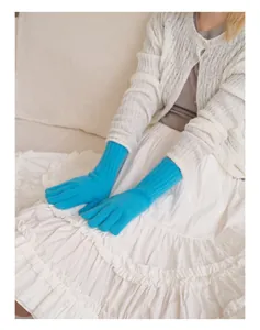 Detail of bright blue long knitted gloves with ribbed texture and warm raccoon wool blend