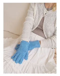 Detail der blauen Grobstrickhandschuhe mit Rippmuster auf einem weißen Kleid gezeigt