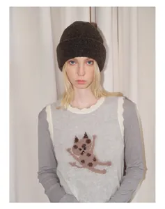 Detail of dark brown wool knit beanie paired with a grey cat pattern sweater vest